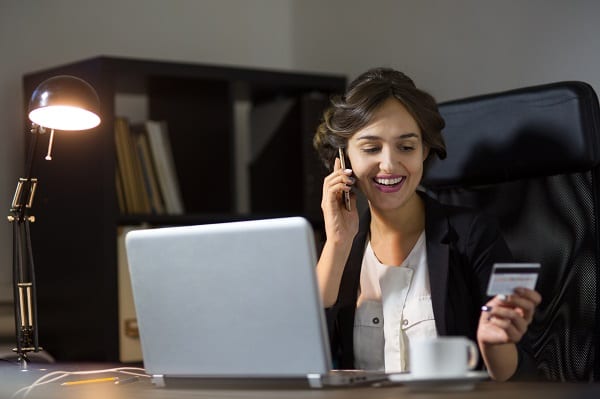 Portrait of a businesswoman sitting at her workplace in office and using credit card and laptop